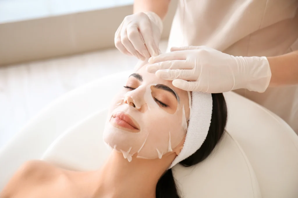 A woman receiving a facial mask treatment in a medspa setting.