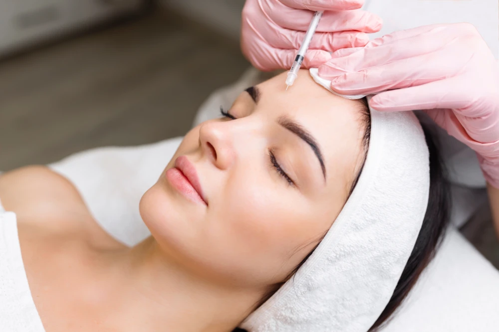 Woman receiving Xeomin injection on forehead at clinic