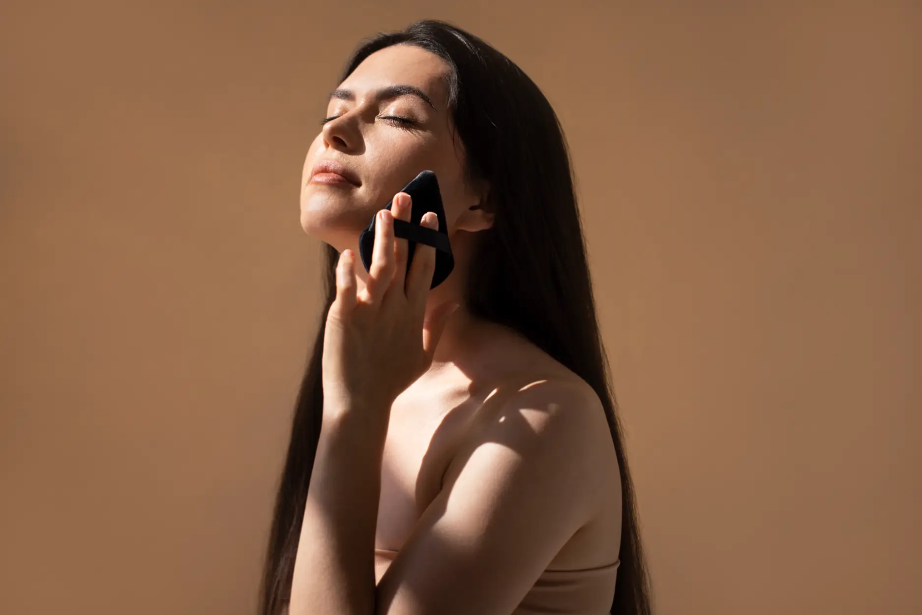Woman using a skincare tool on her cheek with eyes closed
