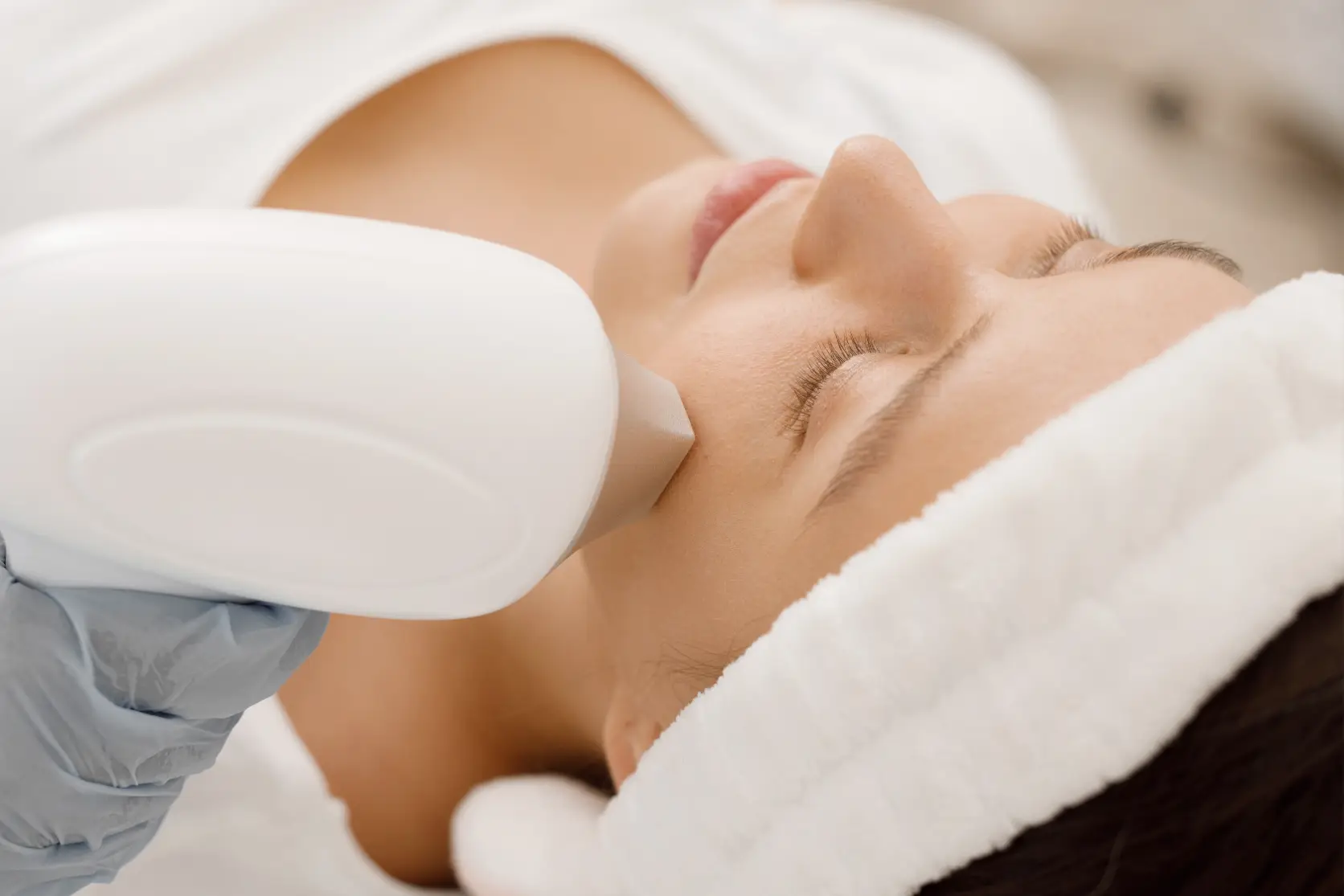 Woman receiving IPL facial rejuvenation treatment with a handheld light therapy device