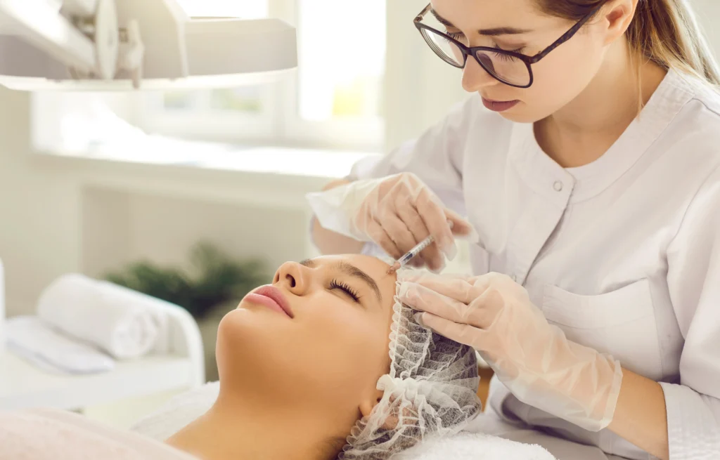 Provider performs an injection near a patient's forehead during a facial aesthetic treatment.